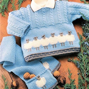 May include: A blue knitted baby sweater with a white collar and a row of sheep on the front. The sweater is paired with a matching blue knitted hat with a sheep on the front.
