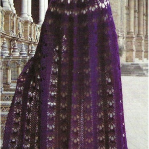 May include: A purple crochet shawl with a lacy pattern. The shawl is draped over a person's shoulders and is flowing in the wind.