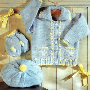 May include: A blue knitted baby cardigan with yellow trim, white buttons, and embroidered flowers. The set also includes a matching blue knitted hat with a yellow pom-pom and a pair of blue knitted mittens with white pom-poms.