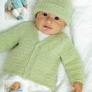 May include: A green knitted baby cardigan with a button fastening and a matching green knitted hat. The cardigan has a textured stitch pattern.
