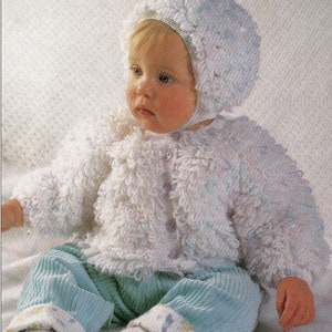 May include: A white crocheted baby jacket and hat set with a fluffy texture. The jacket has a button closure and the hat has a ruffled edge.