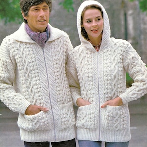 May include: Two white knitted sweaters with a cable knit pattern and zipper closures. The sweater on the left has a collar, while the sweater on the right has a hood.
