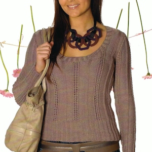 Könnte beinhalten: Eine Frau trägt einen mauvefarbenen Strickpullover mit Rundhalsausschnitt und langen Ärmeln. Sie trägt außerdem einen braunen Gürtel und eine blaue Jeans. Eine beige Handtasche hängt über ihrer Schulter, und eine geometrische Halskette liegt um ihren Hals.