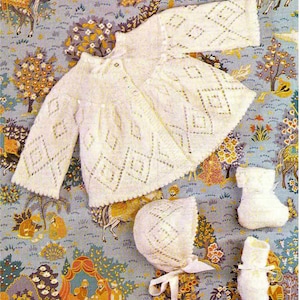 May include: A white knitted baby outfit set with a diamond pattern. The set includes a cardigan, a bonnet, and booties.