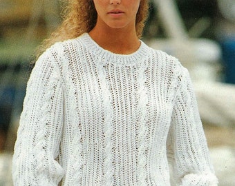 May include: A white knitted sweater with a cable knit pattern. The sweater has a round neckline and long sleeves.