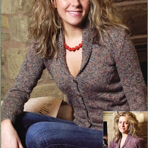 May include: A woman wearing a multi-coloured cardigan with a red beaded necklace and blue jeans. She is sitting on a sofa with a tan throw pillow.