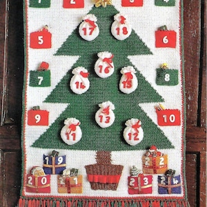 Puede incluir: Un calendario de adviento de Navidad tejido a crochet con forma de árbol de Navidad verde con bolsillos blancos numerados del 1 al 24. Los bolsillos están llenos de pequeños regalos y decoraciones.