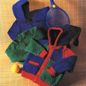May include: Three knitted hooded cardigans in blue, green, and red with a tennis racket in the background.