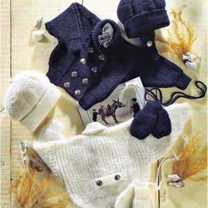 May include: A set of knitted baby clothes in white and navy blue. The set includes a cardigan, a hat, mittens, and booties. The cardigan has a sailor-style collar and buttons. The hat is a simple beanie style. The mittens and booties are both knitted in a simple pattern.