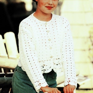 Peut inclure: Un cardigan blanc en crochet avec un devant boutonné et un ourlet festonné. Le cardigan est porté sur un jean bleu.