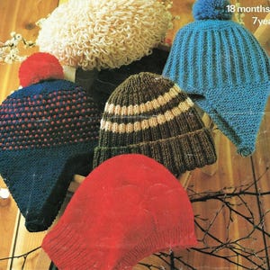 Puede incluir: Cinco gorros de punto de diferentes colores y estilos. Los gorros están hechos de lana y tienen pompones en la parte superior. Los gorros están dispuestos en una fila sobre una superficie de madera.