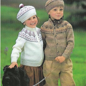 May include: Two children wearing knitted cardigans and hats with pom-poms. The girl is wearing a white cardigan with a purple and white pattern and a purple beret. The boy is wearing a brown cardigan with a brown and orange pattern and a brown hat. They are standing in a grassy field with a black dog.