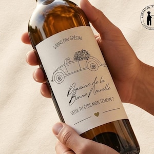 Peut inclure: Une bouteille de vin marron avec une étiquette blanche ornée d'une illustration de voiture transportant des fleurs. L'étiquette indique "Grand Cru Spécial" et "Domaine de la Bonne Nouvelle". La bouteille est tenue par des mains.