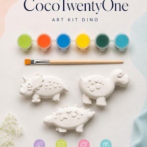 Puede incluir: Un kit de arte con tres figuras de dinosaurios blancos, seis botes de pintura de varios colores y un pincel. El kit está etiquetado como "CocoTwentyOne ART KIT DINO" e incluye iconos de no tóxico, seguro para niños, juego creativo y regalo perfecto.
