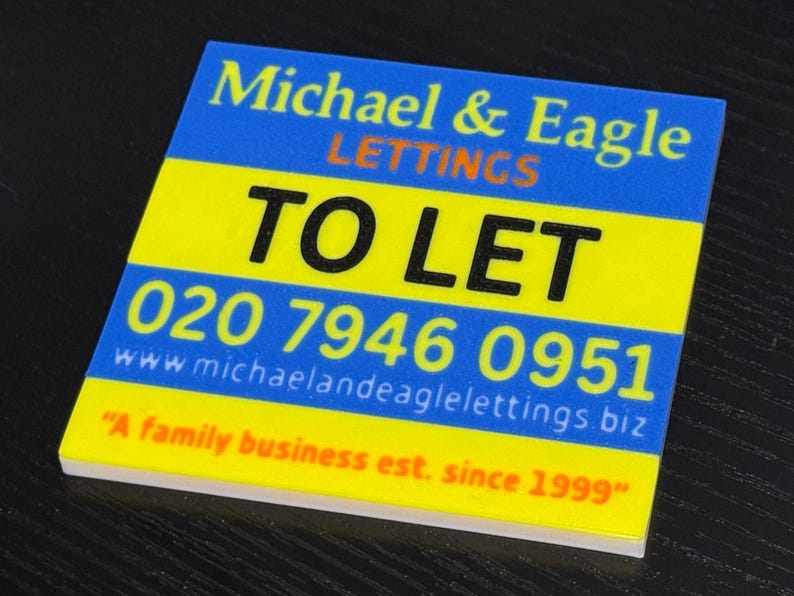 May include: A square sign with the text "Michael & Eagle LETTINGS TO LET" in blue and black. The sign also includes a phone number and website address, with the tagline "A family business est. since 1999".