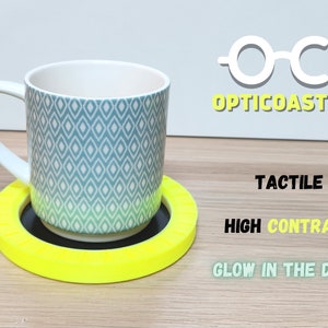 May include: A bright yellow, tactile coaster with a black center. The coaster is designed for high contrast and glows in the dark. The text "OC- OPTICOASTER" is visible in the upper right corner of the image.