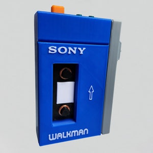 May include: A blue Sony Walkman cassette player with a white cassette tape inside. The player has a white label that says "WALKMAN" and a white label that says "SONY".