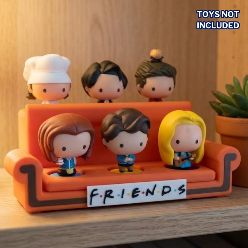 K&ouml;nnte beinhalten: Ein orangefarbenes Miniatursofa mit sechs Charakterfiguren. Die Figuren haben unterschiedliche Frisuren und Outfits. Auf dem Sofa steht das Wort "FRIENDS". Der Text "TOYS NOT INCLUDED" befindet sich in der oberen rechten Ecke.