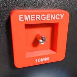 May include: Red plastic emergency access panel with the text "EMERGENCY" and "10MM" in white lettering. A silver socket wrench is visible in the center of the panel.