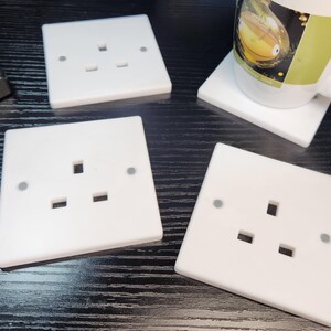May include: Four white plastic electrical outlet covers with three holes each. The covers are on a black surface.