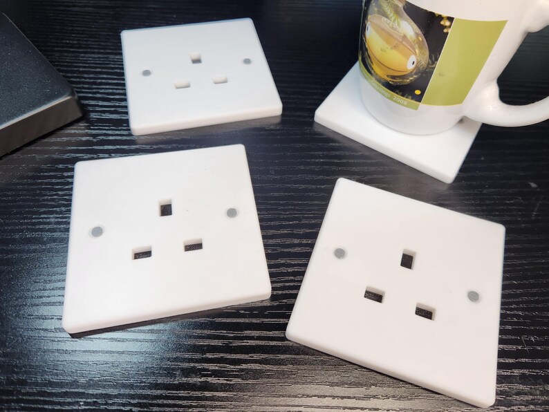 May include: Four white plastic electrical outlet covers with three holes each. The covers are on a black surface.