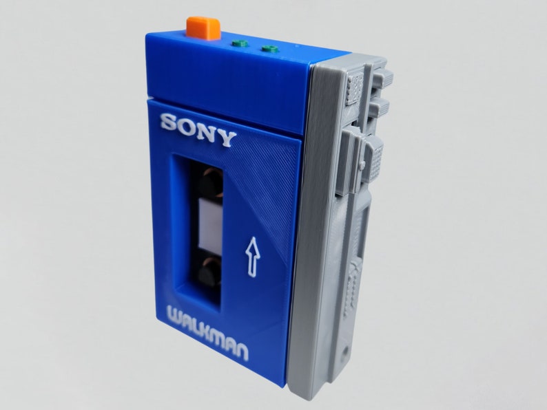 May include: A blue and gray Sony Walkman cassette player with a cassette tape slot and the text "WALKMAN" on the front.