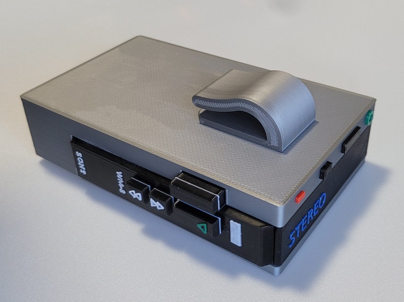 May include: A gray and black portable stereo cassette player with a matching gray clip. The player has buttons, ports, and the word "SONY" printed on the front. The word "STEREO" is printed on the side.