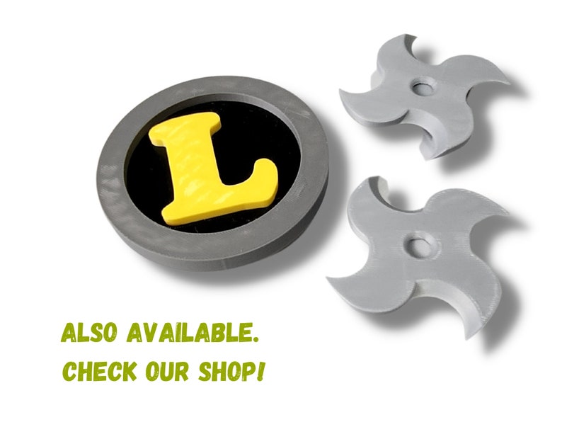 May include: A gray, circular emblem with a yellow "L" inside a black circle, and two gray, four-pointed ninja stars. The text "ALSO AVAILABLE. CHECK OUR SHOP!" is in green.