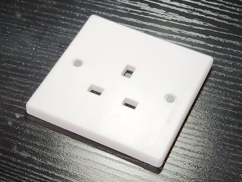 May include: A white plastic electrical outlet with three prongs. The outlet is designed for use in the United Kingdom.