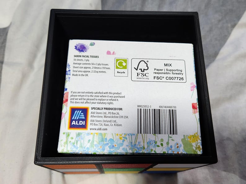 May include: A box of Saxon Facial Tissues with a floral design. The box is made of recycled paper and is certified by the Forest Stewardship Council (FSC). The box contains 56 sheets of 3-ply tissues. The box is made in the UK.