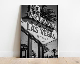 May include: Black and white framed print of the iconic "Welcome to Fabulous Las Vegas Nevada" sign. The sign features the text "To Fabulous Las Vegas" and is adorned with lights. Palm trees and a Harley-Davidson sign are also visible.
