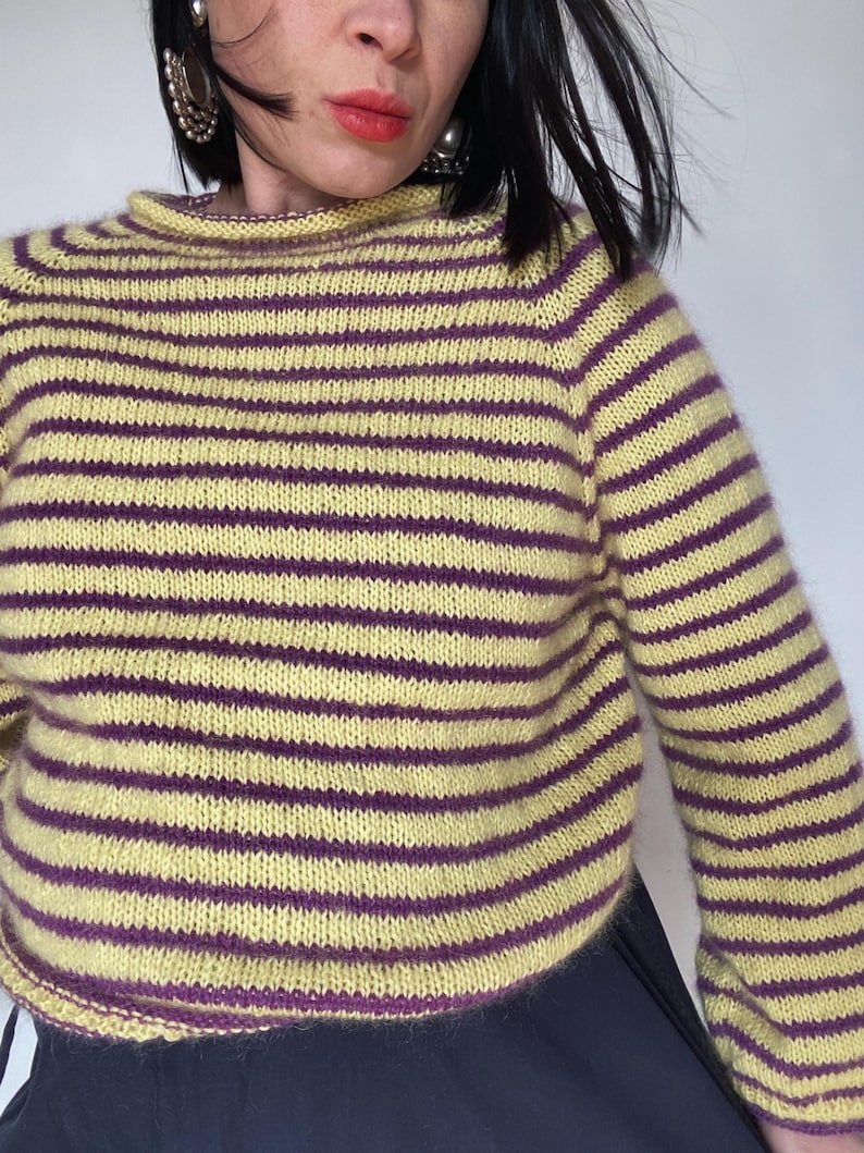 Puede incluir: Un su&eacute;ter a rayas amarillas y moradas con cuello redondo. El su&eacute;ter tiene mangas largas y un dise&ntilde;o ajustado. Las rayas son horizontales y espaciadas uniformemente. La combinaci&oacute;n de colores es una mezcla de amarillo claro y morado oscuro.