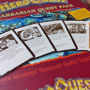 May include: A close-up of a board game box and cards. The box reads "HERO QUEST BARBARIAN QUEST PACK". The cards feature illustrations and text, including "Warhorn of Command" and "Spiked Shield".