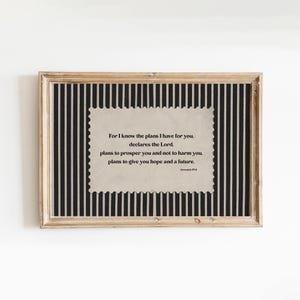 May include: Framed print with a beige background featuring a quote from Jeremiah 29:11. The quote is in black text and is set against a black and white striped background. The frame is a light brown color.