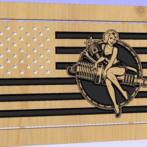 May include: Wooden American flag with a carved design. The flag features black stripes and a field of stars. A pin-up girl graphic is on the right side, with a black and tan color scheme. The artwork is a decorative piece.