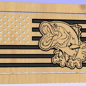 Può includere: Arte da parete in legno raffigurante una bandiera americana con un pesce persico scolpito. La bandiera presenta stelle e strisce, con il pesce sovrapposto alle strisce. L'opera d'arte è realizzata in legno chiaro con dettagli neri.