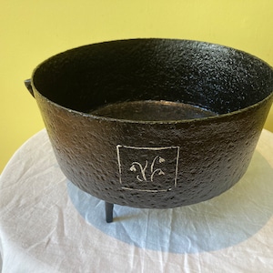 Peut inclure: Jardinière en fonte noire avec trois pieds et un motif blanc de fleurs stylisées dans un cadre carré.