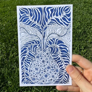 May include: A blue and white illustration of a vase filled with flowers. The vase is surrounded by a pattern of blue and white leaves.