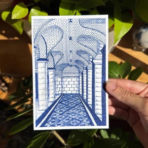May include: A blue and white pen and ink drawing of a long hallway with arched ceilings and brick walls. The perspective drawing shows a detailed architectural interior with a patterned floor and symmetrical design.