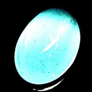 Peut inclure: Objet ovale bleu clair avec une finition brillante. Le dégradé de couleur passe d'une teinte plus foncée en haut à une teinte plus claire en bas. De petits points sombres sont dispersés sur la surface, sur fond noir.