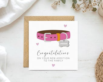 May include: A square greeting card featuring a pink dog collar with a silver buckle and a bone-shaped tag that reads MINNIE. The text below says Congratulations on your new addition to the family, accented by three small pink hearts.