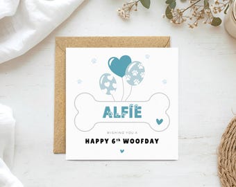 May include: A square greeting card with a brown envelope featuring a white bone graphic containing the name ALFIE in blue letters. Above the bone are three blue balloons with heart and paw print patterns. The text reads WISHING YOU A HAPPY 6TH WOOFDAY.