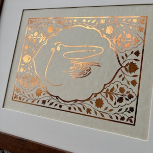 Peut inclure: Œuvre d'art encadrée avec calligraphie dorée sur fond crème. La calligraphie est entourée d'une bordure florale, le tout encadré d'un passe-partout blanc et d'un cadre en bois marron foncé. Esthétique traditionnelle.
