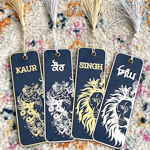 Può includere: Quattro segnalibri neri con disegni di leoni dorati e bianchi e testo. I segnalibri presentano i nomi "Kaur", "Singh" e "Gill" in inglese e punjabi.