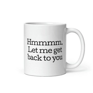 May include: White ceramic coffee mug with black text that reads "Hmmmm. Let me get back to you."