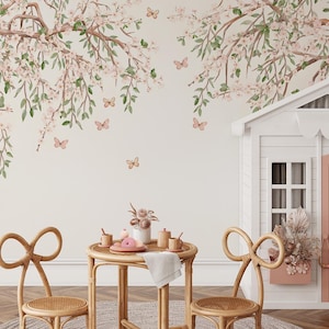 May include: A whimsical interior scene featuring a playhouse and a small table set for tea. The walls are adorned with a floral mural of cherry blossoms and butterflies. Two bow-shaped chairs surround the table, creating a charming and inviting space.