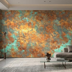 May include: A modern living room featuring a large wall with a textured, abstract design in shades of orange, teal, and gold. The room includes a gray sofa, a glass coffee table, and a tall, slender floor lamp.