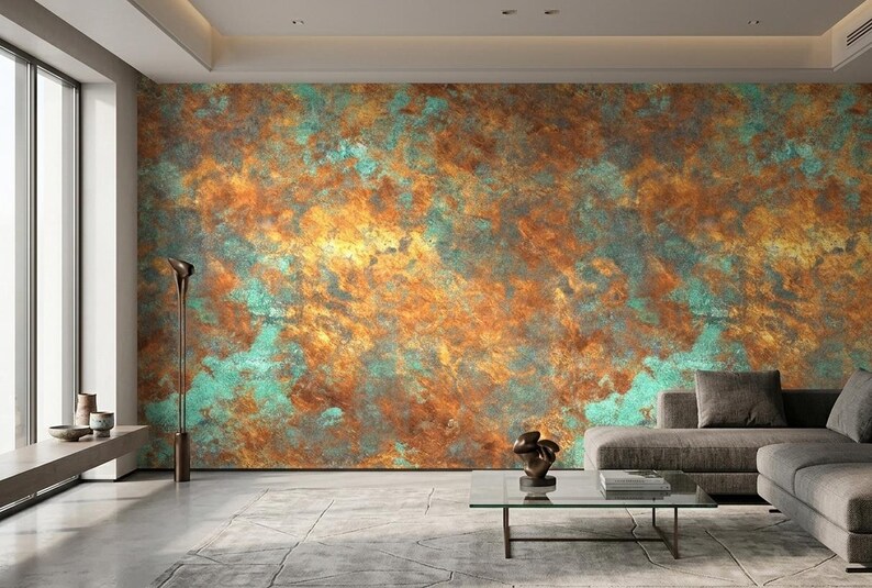 May include: A modern living room featuring a large wall with a textured, abstract design in shades of orange, teal, and gold. The room includes a gray sofa, a glass coffee table, and a tall, slender floor lamp.