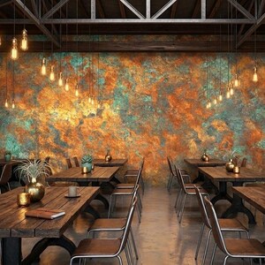 May include: Interior shot of a restaurant with wooden tables and chairs. The walls are decorated with a textured, colorful mural. Hanging lights illuminate the space. The overall theme is rustic and industrial.