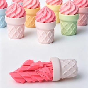 May include: A collection of small ice cream cone-shaped objects with pink swirled tops and pastel-colored bases featuring a diamond-patterned texture. One object is positioned horizontally, revealing a bright pink, layered, fan-like interior.
